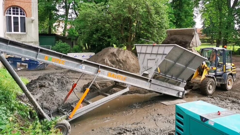 Loader that feeds a construction site conveyor belt with a bucket