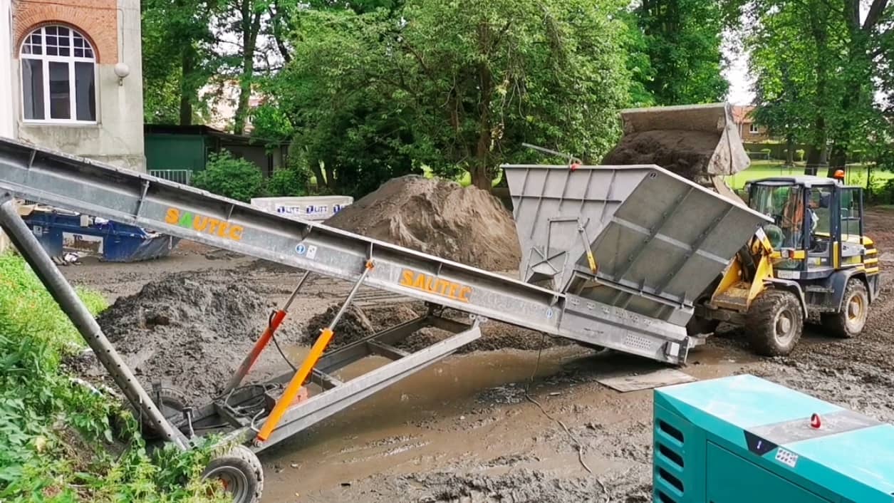 Loader that feeds a construction site conveyor belt with a bucket
