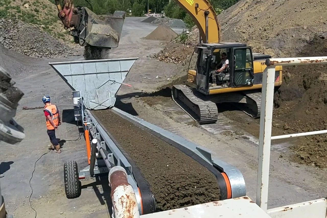 Alimentation d'un tapis transporteur au godet cribleur.