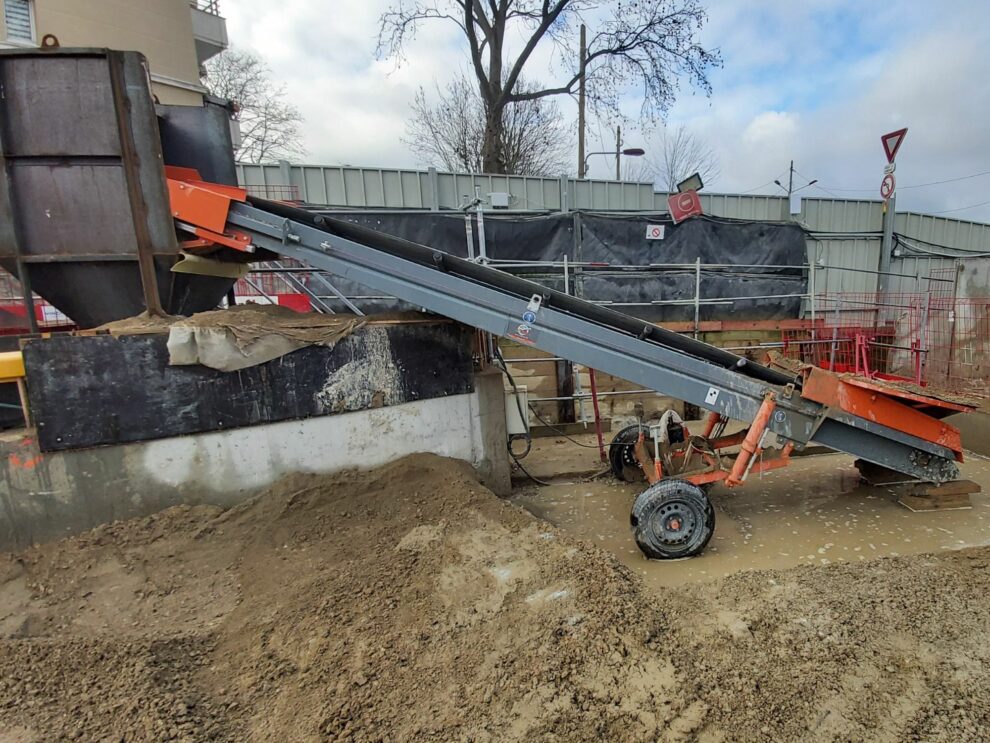 Een transportband voor grond die een materiaalzuil voedt.