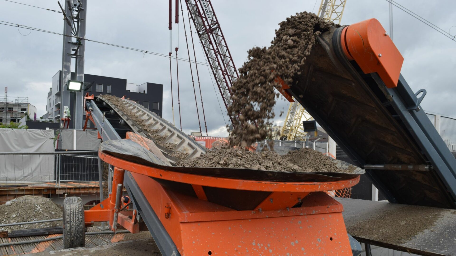 Un convoyeur pour terre sur un chantier urbain de construction.