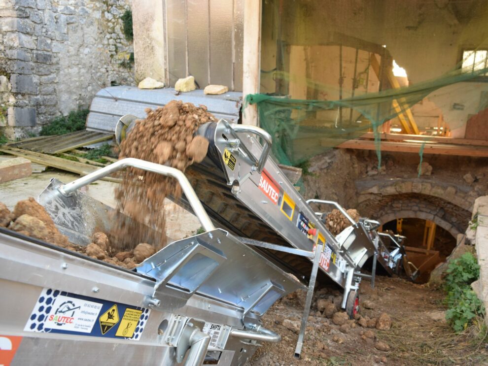 Mini transportbanden die op een bouwplaats worden gebruikt om grond en puin uit een kelder af te voeren.