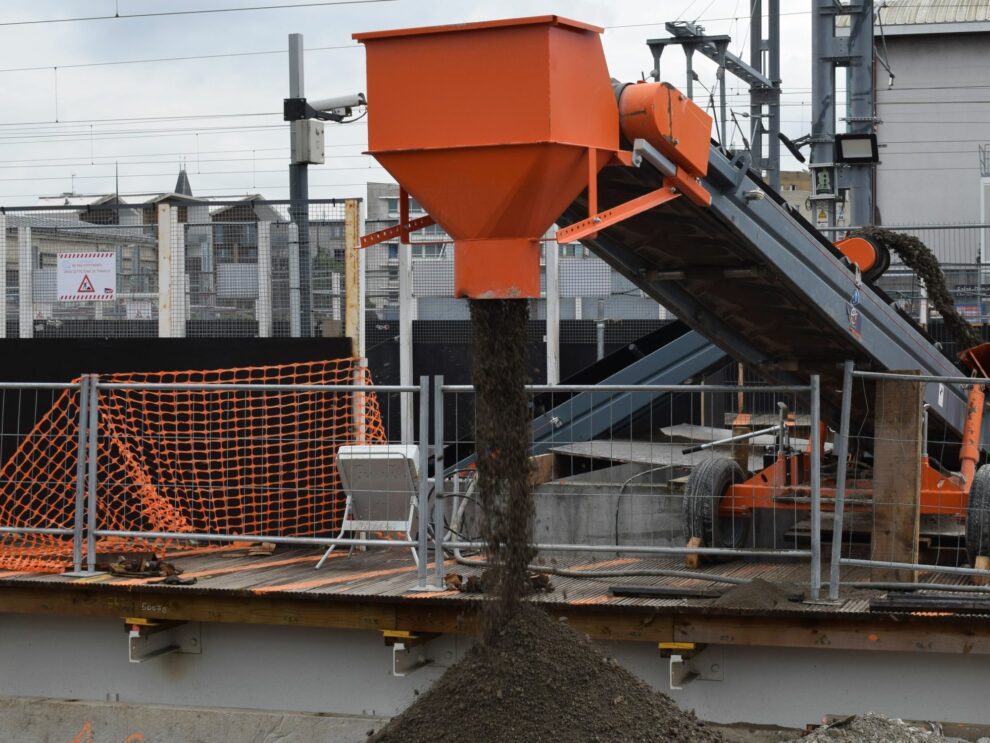 Een hoop aarde die door een transportband en de storttrechter ervan in vorm wordt gebracht.